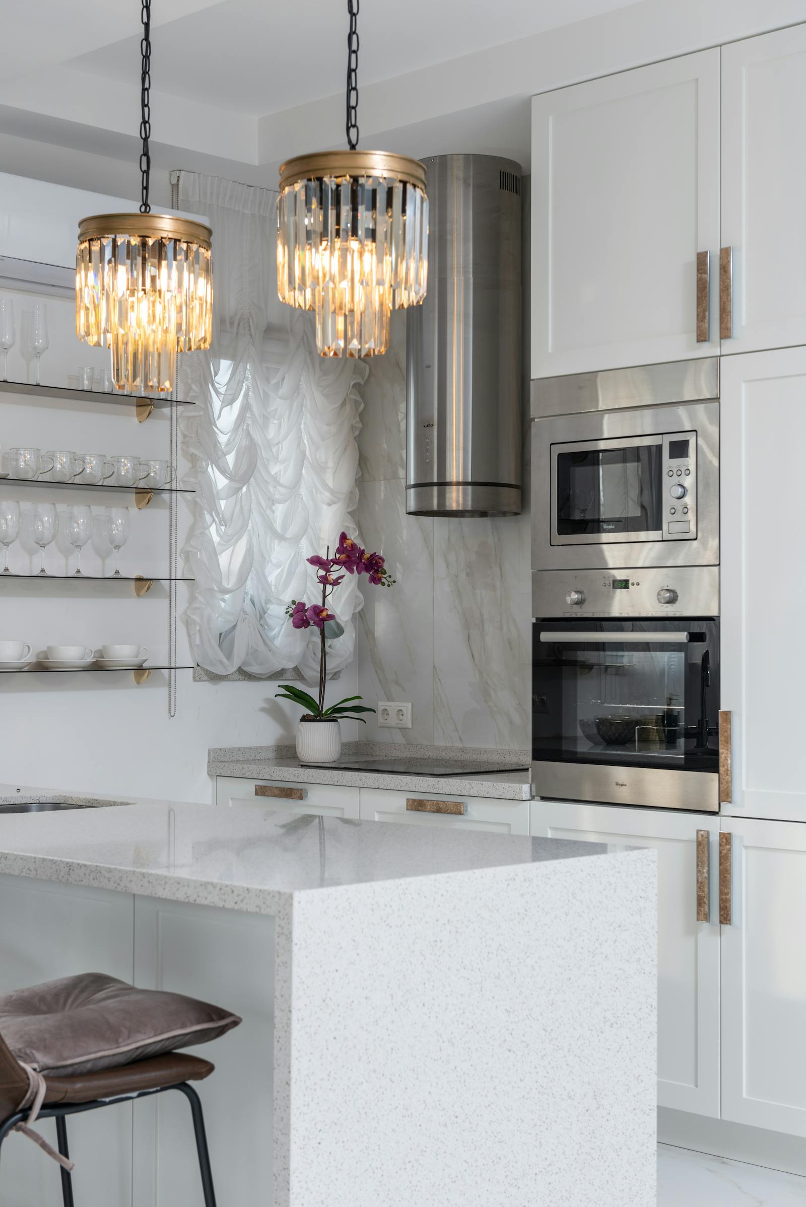 Modern white kitchen with marble countertops and designer pendant lighting
