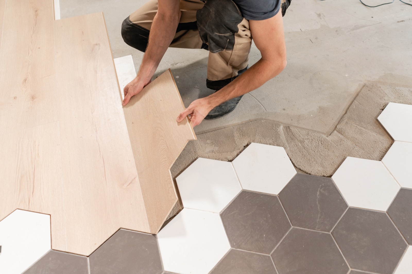 Professional floor tile installation — wood laminate and hexagonal ceramic tiles by Yoline Construction